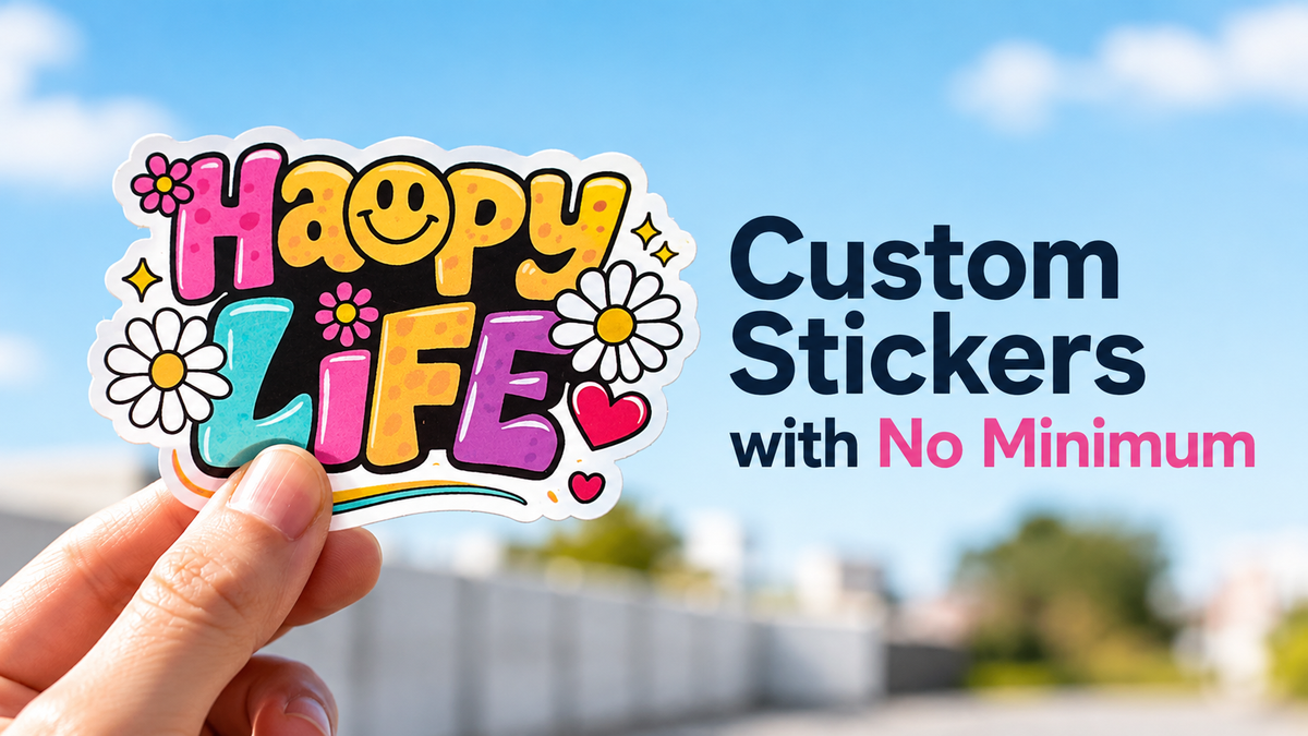 A person's hand holds a "Happy Life" themed die cut sticker with a white border. The background is a blurred outdoor scene with a blue sky.