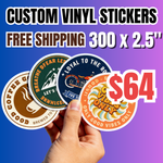 Promotional banner for '300 custom vinyl stickers (2.5") for $64 with free shipping'. A hand holds a fan of four circular premium vinyl stickers featuring coffee, mountain, motorcycle, and "Good Vibes Only" designs. The image uses a blue-to-purple gradient background