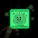 Glowing green sticker with cat illustration held in hand against dark background, great for creative design.