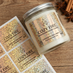 Custom gold glitter labels applied on a glass soy candle jar alongside printed sheets, showcasing premium sparkly personalized labels for home decor.