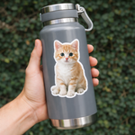 Gray water bottle with a cat design sticker held by a hand against a green leafy background