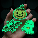 Glowing Halloween-themed stickers (pumpkin, bat, ghost) in Full CMYK color print held in a hand against a dark background.