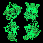 Set of four green Halloween-themed glowing stickers on a black background