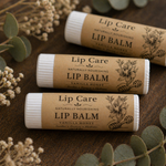 Three lip balms labeled 'Lip Care' with vanilla honey flavor on a wooden surface with greenery.