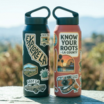 Two water bottles with LA-themed Stickers on a wooden surface with a blurred natural background.
