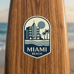 Wooden surfboard with a 'Miami Beach' waterproof stickers on a beach background