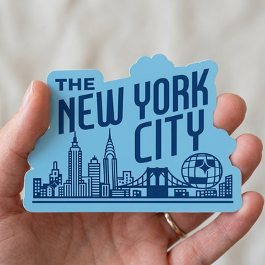 Blue 'The New York City' sticker held in a hand with a blurred background