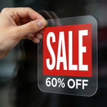 Hand holding a 'SALE 60% OFF' sign static clings promotion decal against a blurred window background