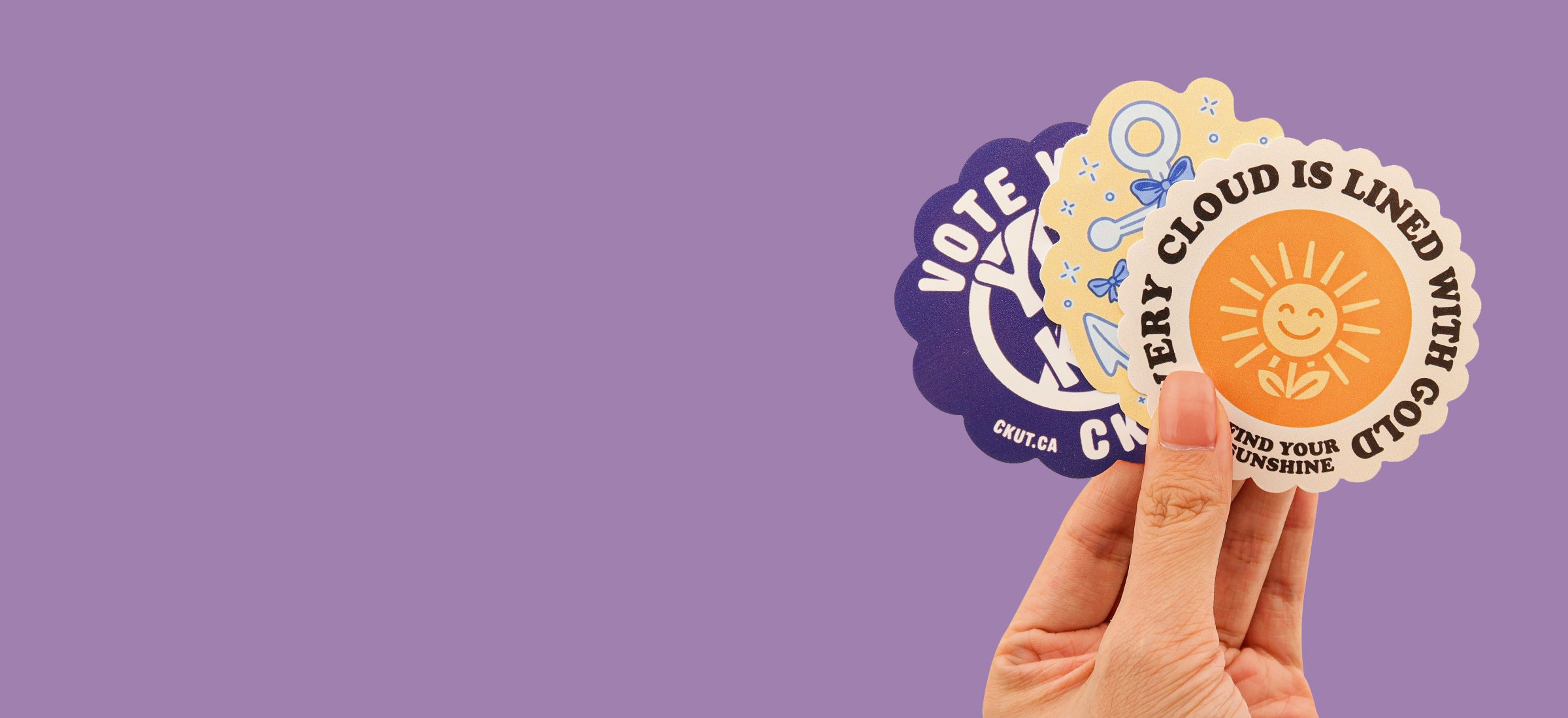 Hand holding custom vinyl die cut stickers with illustrations and graphic images of smiling sunflower and positive messages