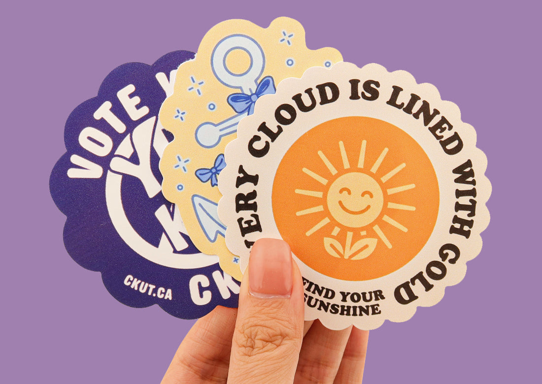 Hand holding custom vinyl die cut stickers with illustrations and graphic images of smiling sunflower and positive messages