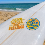 Surfboard displaying "Catch Waves, Not Feelings" and ocean-themed stickers