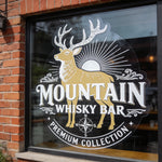Reusable large Christmas window cling of Mountain Whisky Bar with a deer logo on a brick building.