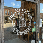 personalized window clings featuring artisan logo with pottery wheel design, applied to a brick storefront glass door for handmade retail branding