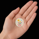 A 1 inch circle sticker featuring a cute flower and sun design held in a person's palm to show the actual size for custom round stickers printing.