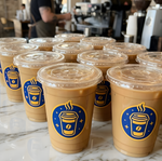 Stack of iced coffee cups featuring custom blue and yellow coffee logo stickers.
