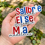 Colorful custom die-cut name stickers displayed in a hand outdoors.