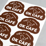 OK Cafe die cut labels on a white sheet with a gray background
