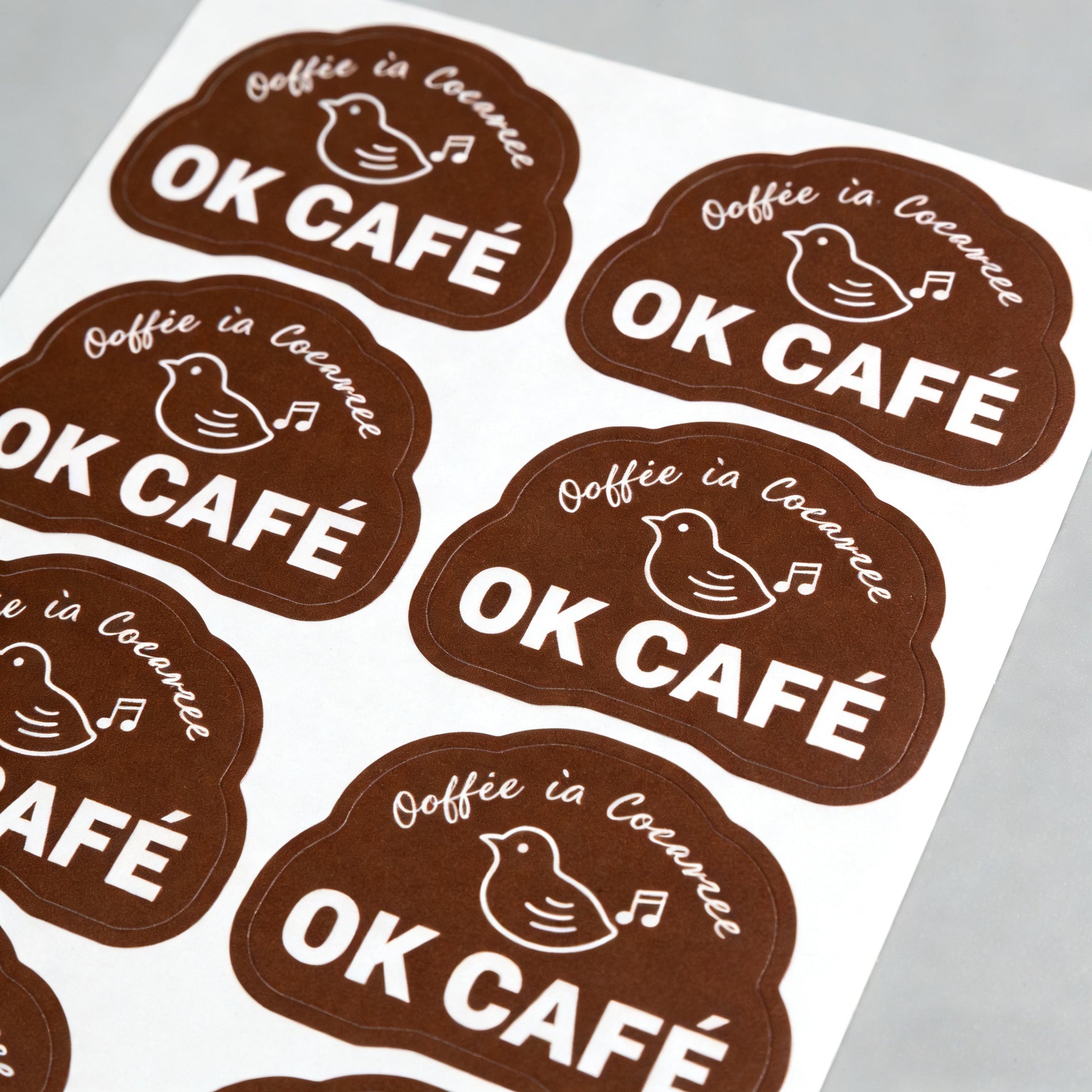 OK Cafe die cut labels on a white sheet with a gray background