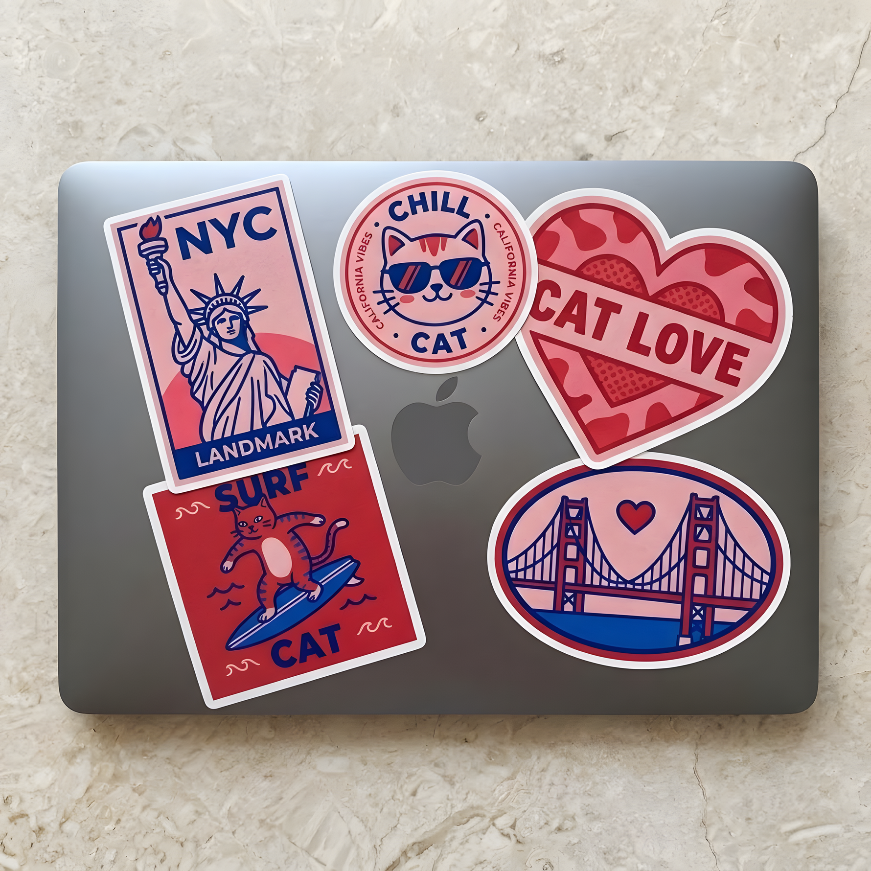 A sleek laptop decorated with cute cat, NYC, and golden gate bridge themed stickers in red, blue, and pink colors.