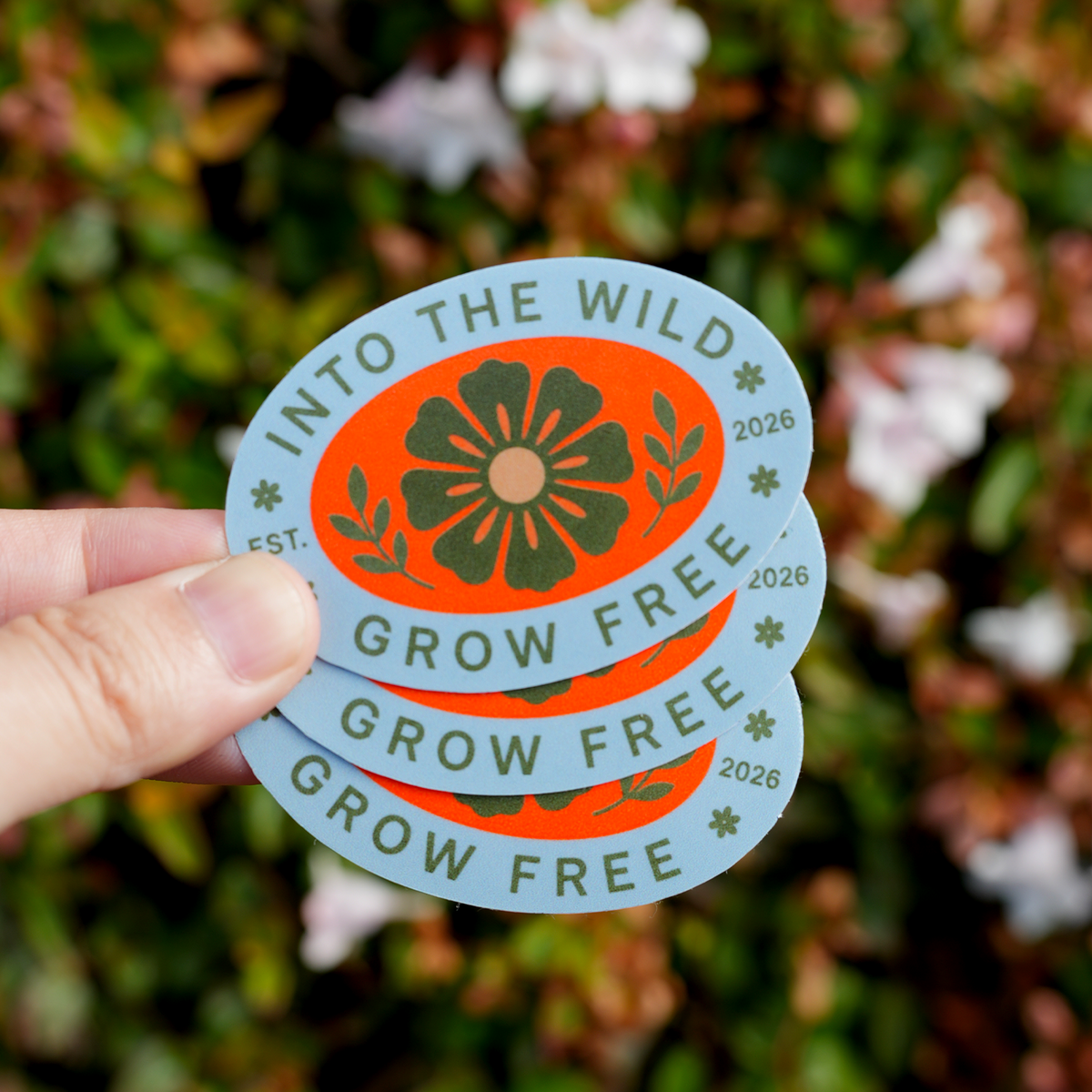 Custom oval stickers with a floral Grow Free design held outdoors