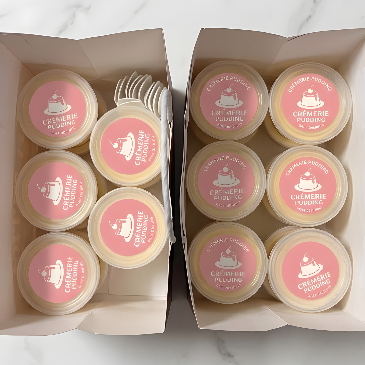 Paper bags filled with Crèmerie Pudding containers featuring custom pink logo stickers.