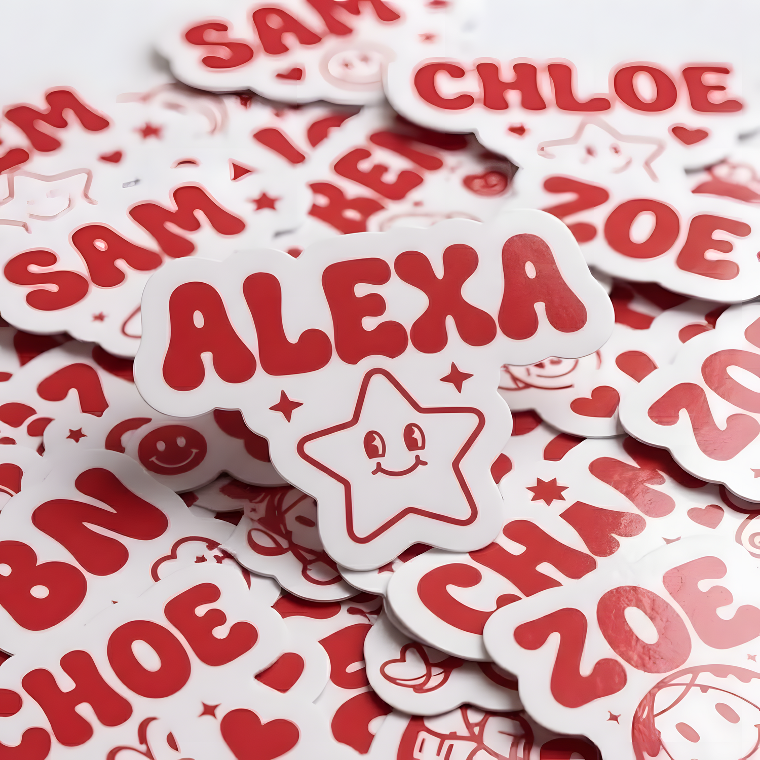 Pile of red and pink custom die-cut name stickers with names and playful decorative icons.