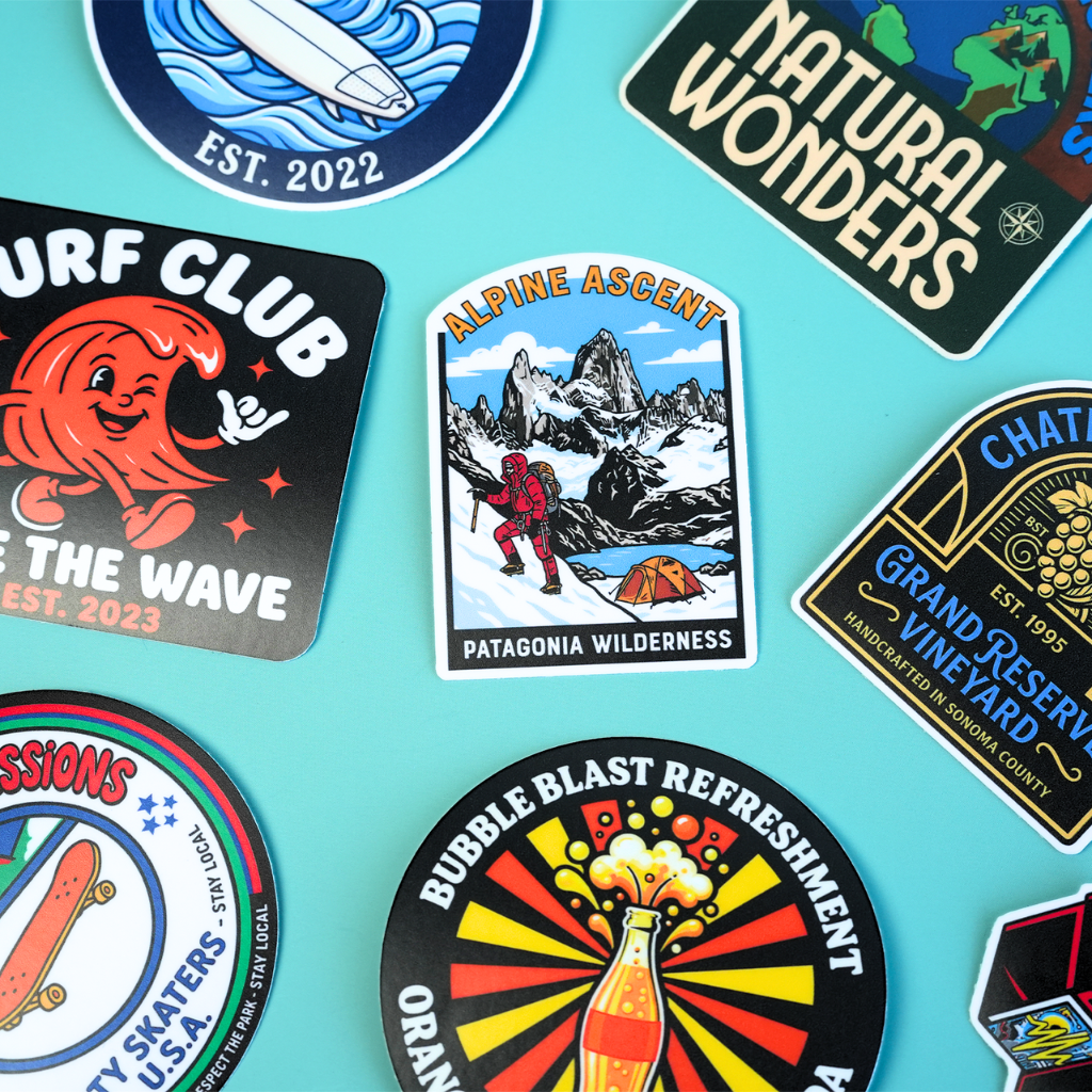 Hand holding colorful custom vinyl stickers featuring truck, surf and skeleton DJ designs.
