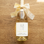 Custom wedding champagne bottle label featuring a bride and groom silhouette in elegant gold and white, personalized with names and wedding date.