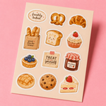 High-end macro photography of a cute bakery sticker sheet featuring matte vinyl stickers of croissants, cupcakes, strawberry jam, and freshly baked bread on a pink background, shot in natural daylight.