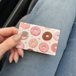 Hand holding a cute donuts debit card skin featuring sweet glazed pastry patterns, a fun credit card cover and decal.
