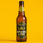 A single brown beer bottle featuring a premium custom black and yellow brewery label for Ironwheel Brewing Co's Spark Line West Coast IPA, isolated on a clean yellow background.