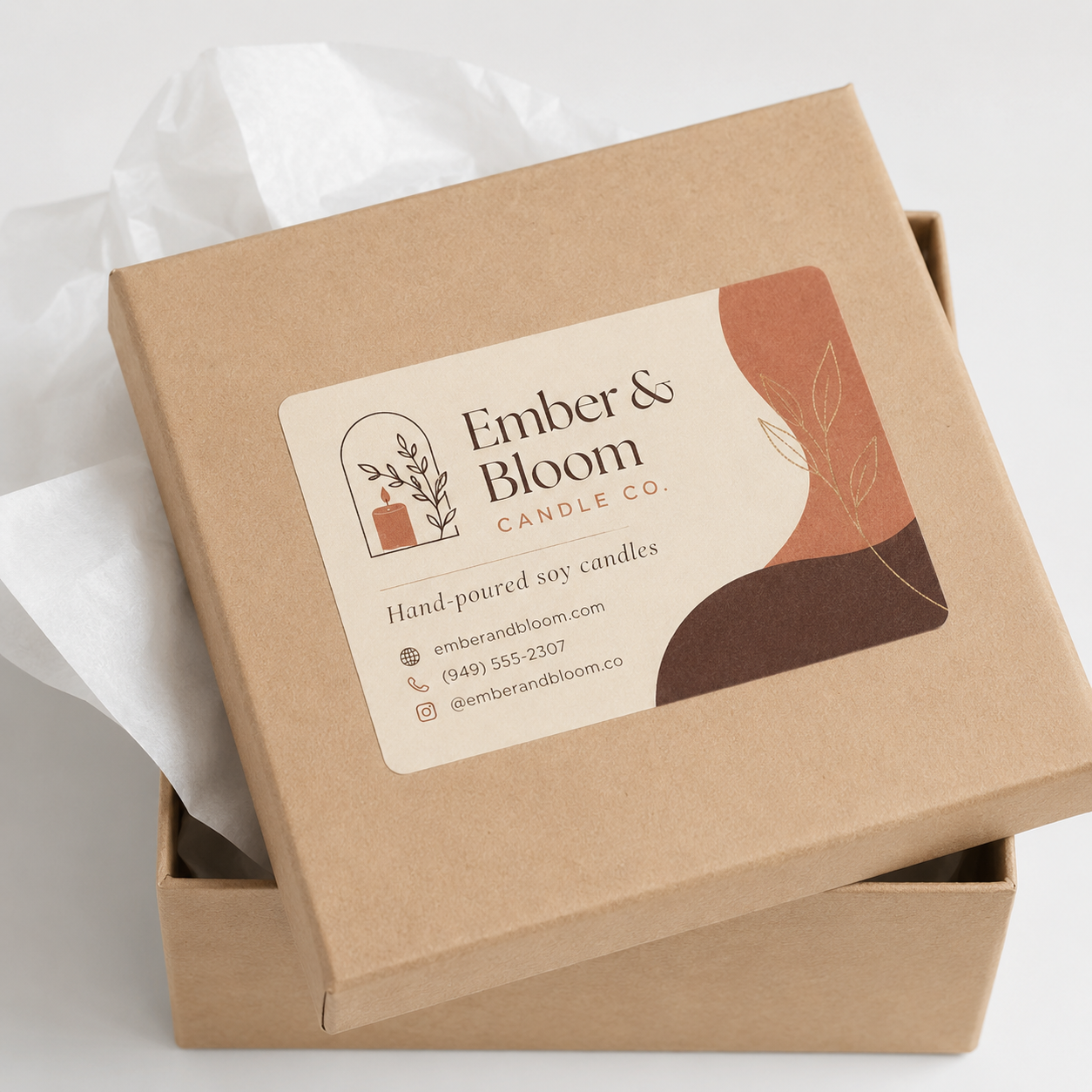 A premium rectangle vinyl branding sticker with rounded corners affixed perfectly onto a brown kraft cardboard gift box filled with white tissue paper.