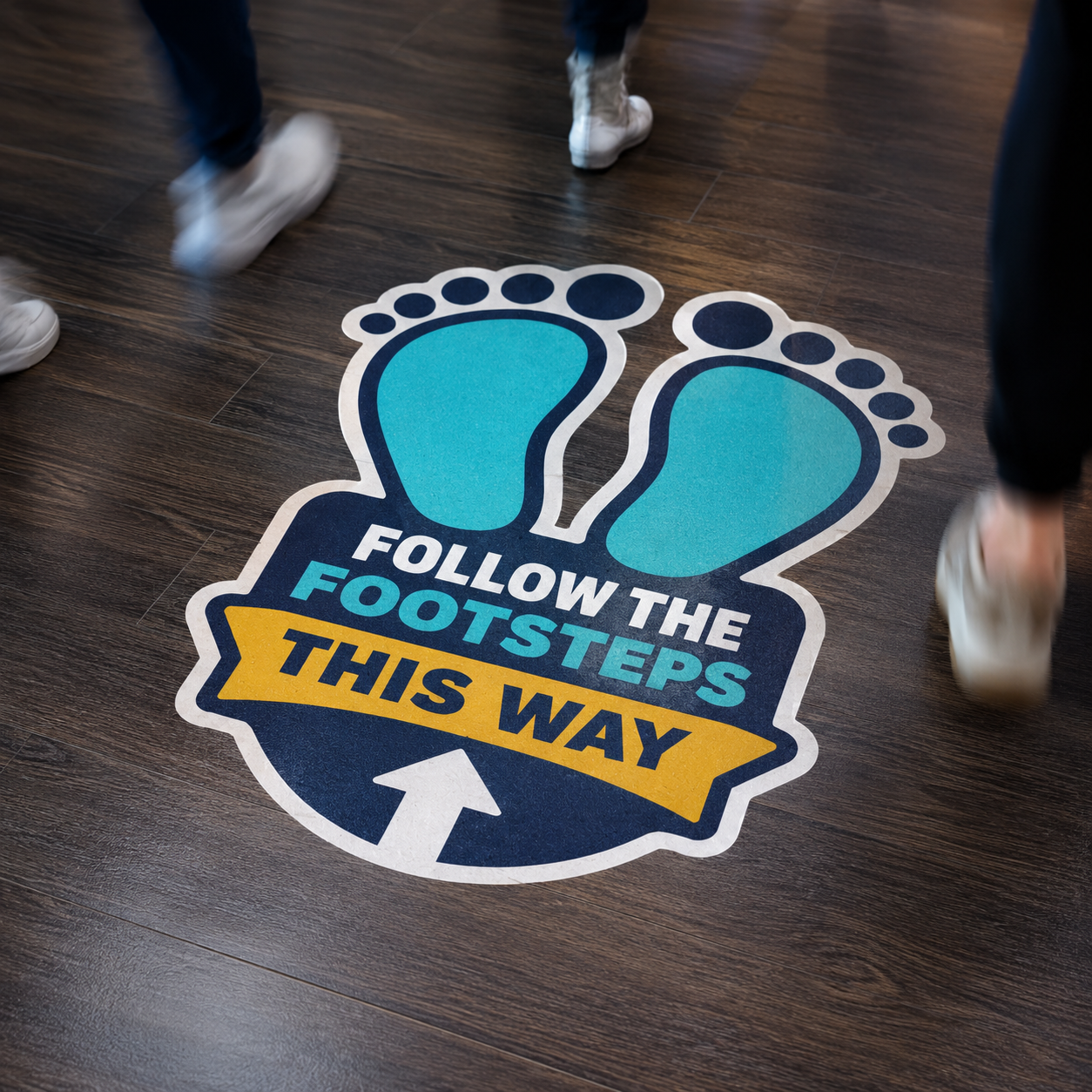 Creative wayfinding floor sticker with blue footprint graphics and "Follow the Footsteps This Way" text, showing people walking over it on a commercial wood-textured floor.