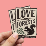 Hand holding rectangle stickers with Love Our Forests squirrel design