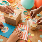 Multiple hands applying circular "Happy Birthday" stickers onto brown gift boxes, blue envelopes, and cupcake containers, showcasing versatile party favor labeling ideas.