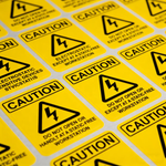 A sheet of yellow heavy duty labels with black caution symbols and text for electrostatic sensitive devices, featuring permanent adhesive for industrial workstations.