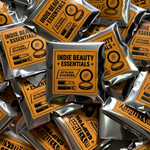 Pile of Indie Beauty Essentials custom stickers in silver foil packaging.