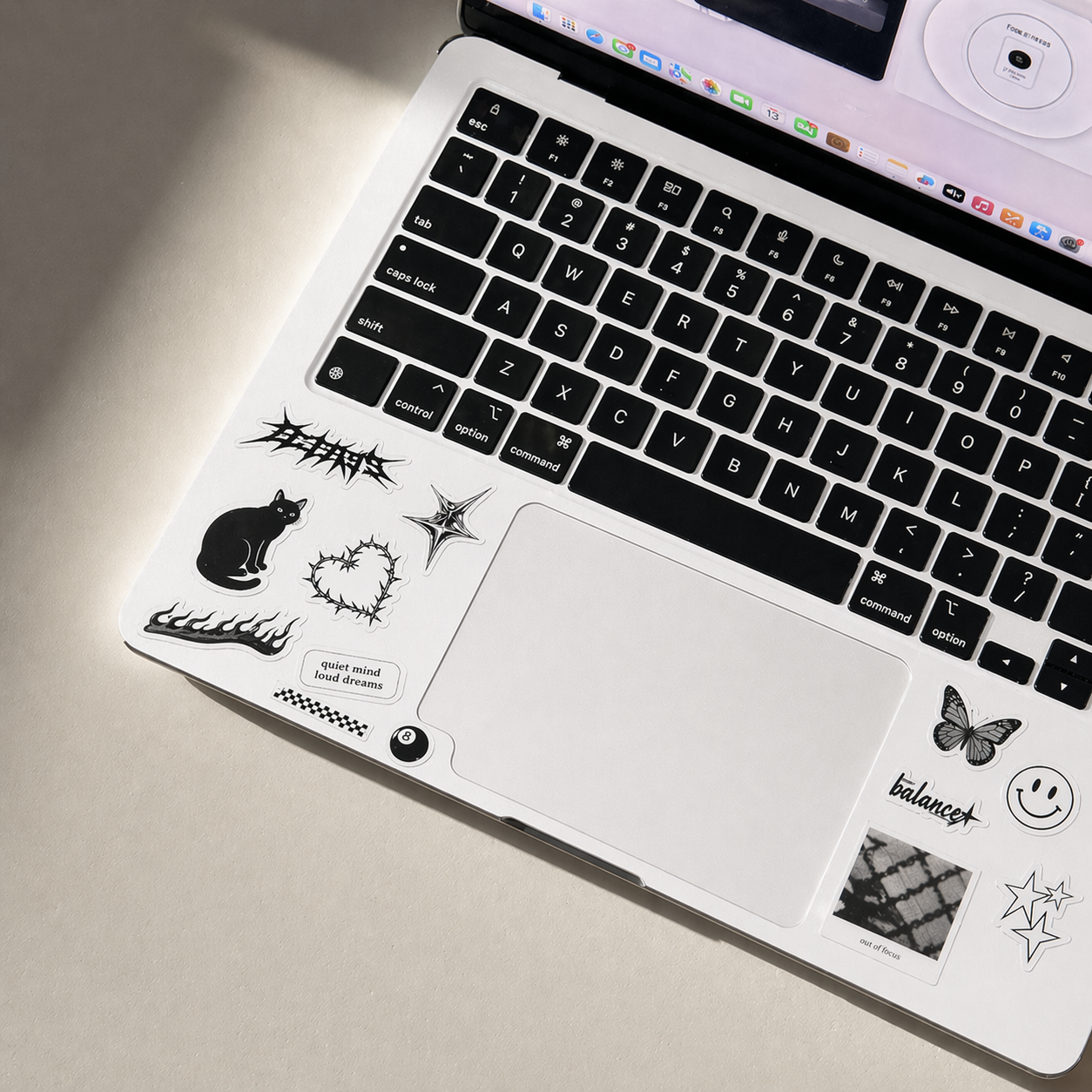 macbook air computer with black keyboard and various stickers on a beige surface, no minimum order
