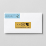 Minimalist custom address labels in blue and yellow applied to a white business envelope.