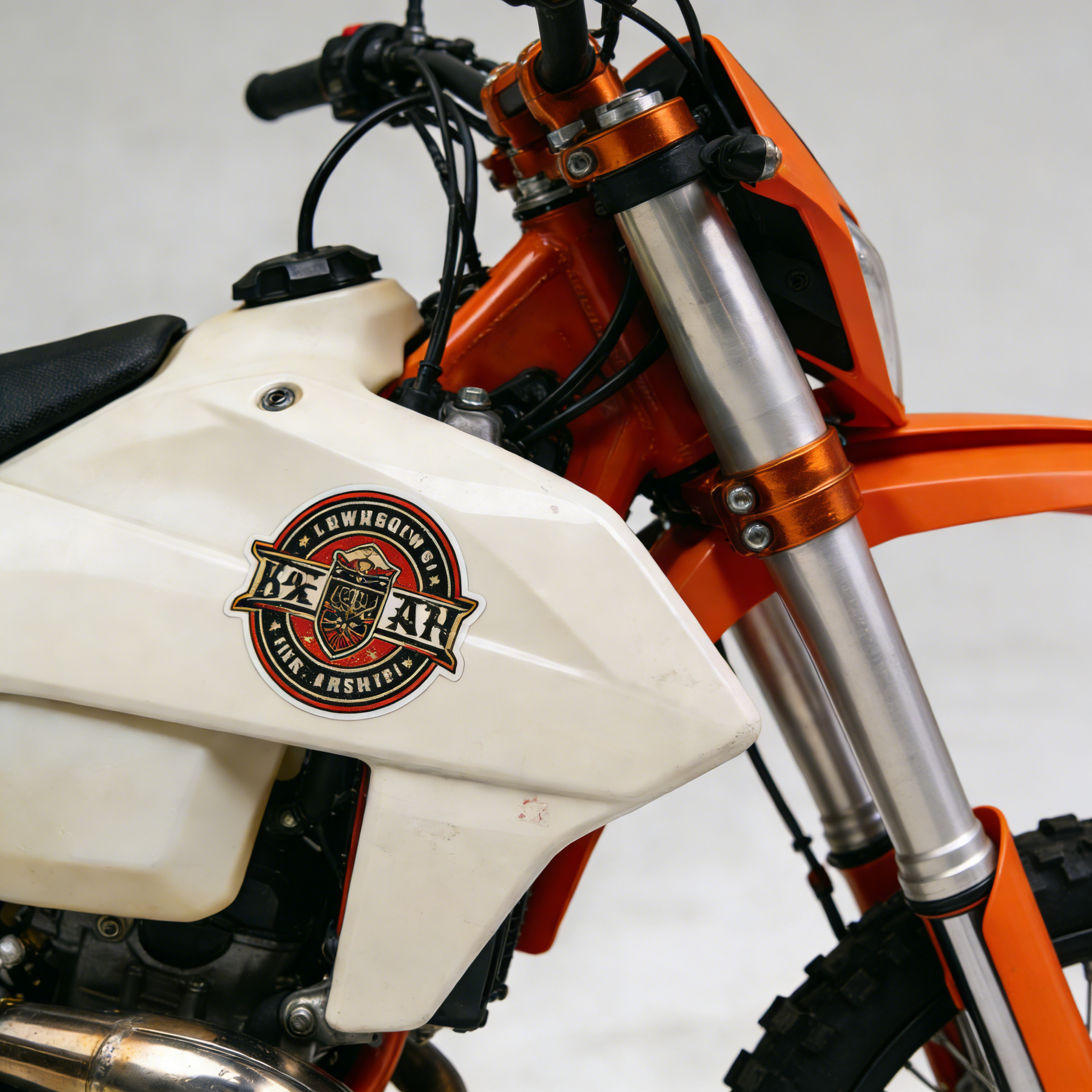 Close-up of an orange and white motorcycle featuring a brand logo with heavy-duty, thick stickers.