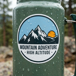 Waterproof outdoor sticker with mountain adventure design applied on bottle in rainy conditions