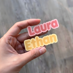 Pastel Laura and Ethan personalized name stickers held in one hand.