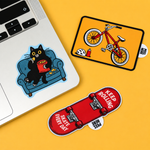 Assortment of peel tab stickers including a cat on a laptop, a bicycle, and a skateboard with a peel-here tab.