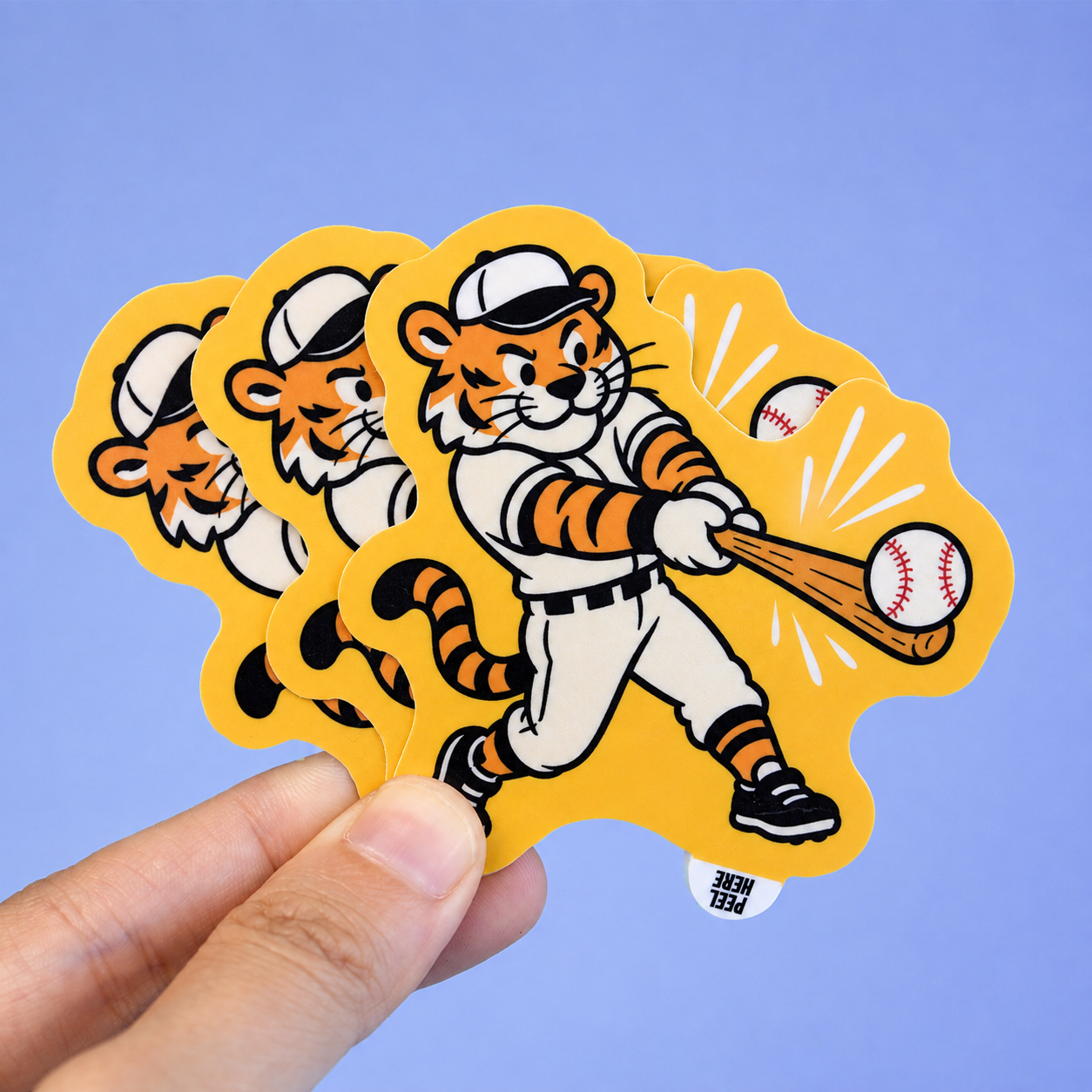 Hand holding custom baseball tiger die-cut peel tab stickers with an easy-peel tab at the bottom.