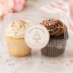 A close-up of a personalized round sticker on a clear cupcake box that says "Ella's Birthday" with a custom date, highlighting high-quality printing on removable vinyl.