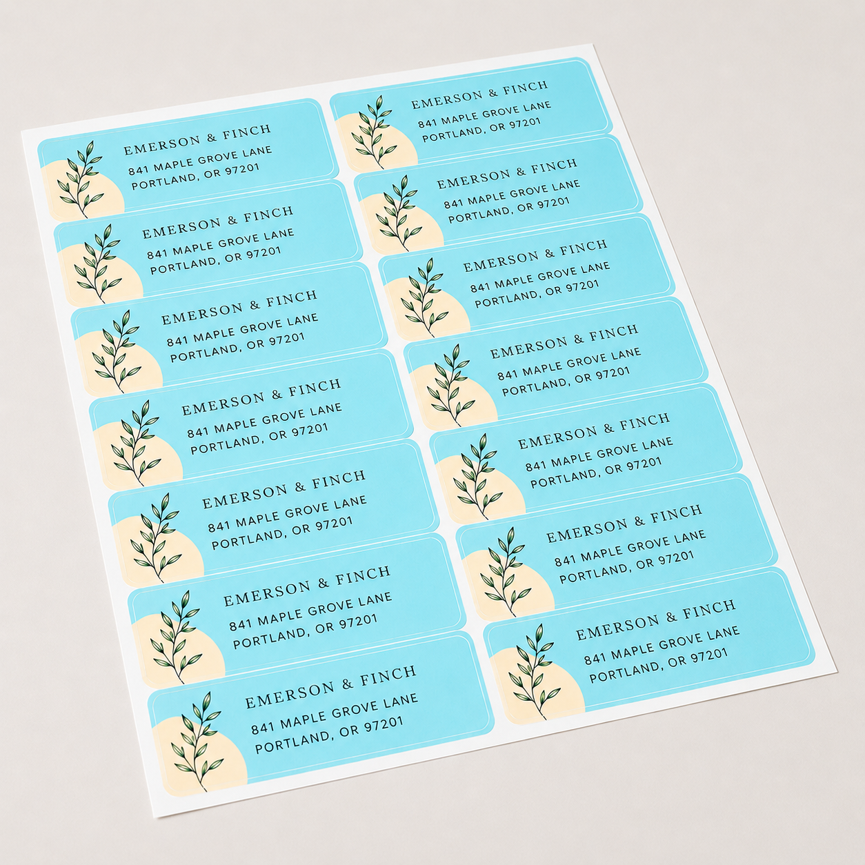 A full sheet of personalized light blue rectangular labels with elegant botanical illustrations and business address text.