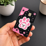 Hand holding a pink and black paw print debit card sticker, a custom credit card cover and decal design.