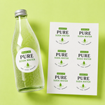 Custom waterproof labels featuring a pure soda water design applied on a glass beverage bottle and sticker sheet.