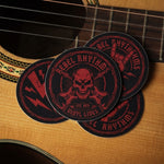 Round custom band stickers featuring a rebel rhythms skull and cross-guitars design on a guitar surface.