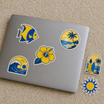 Removable vinyl stickers with tropical coastal designs in blue and yellow applied on a laptop in a flat-lay product photo.